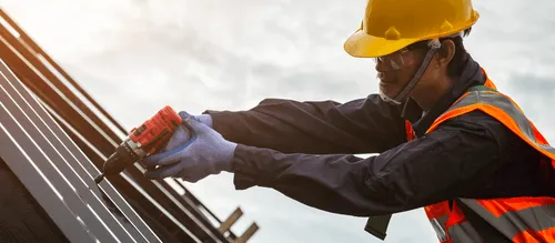 Technician inspecting solar panels on facility roof during routine exterior maintenance work